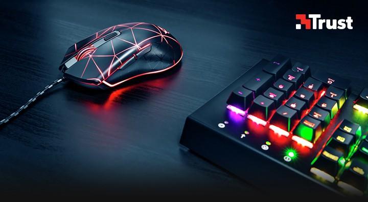 Mouse gamer com iluminação LED ao lado de teclado mecânico RGB em mesa escura